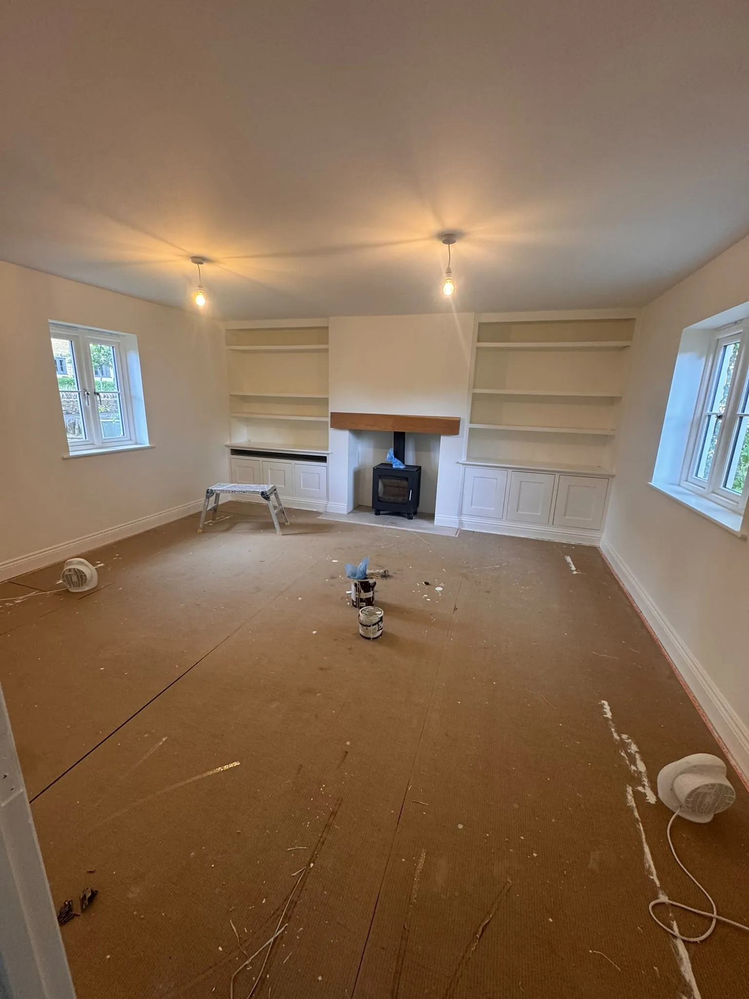 Living room with fireplace and alcoves prepared and painted